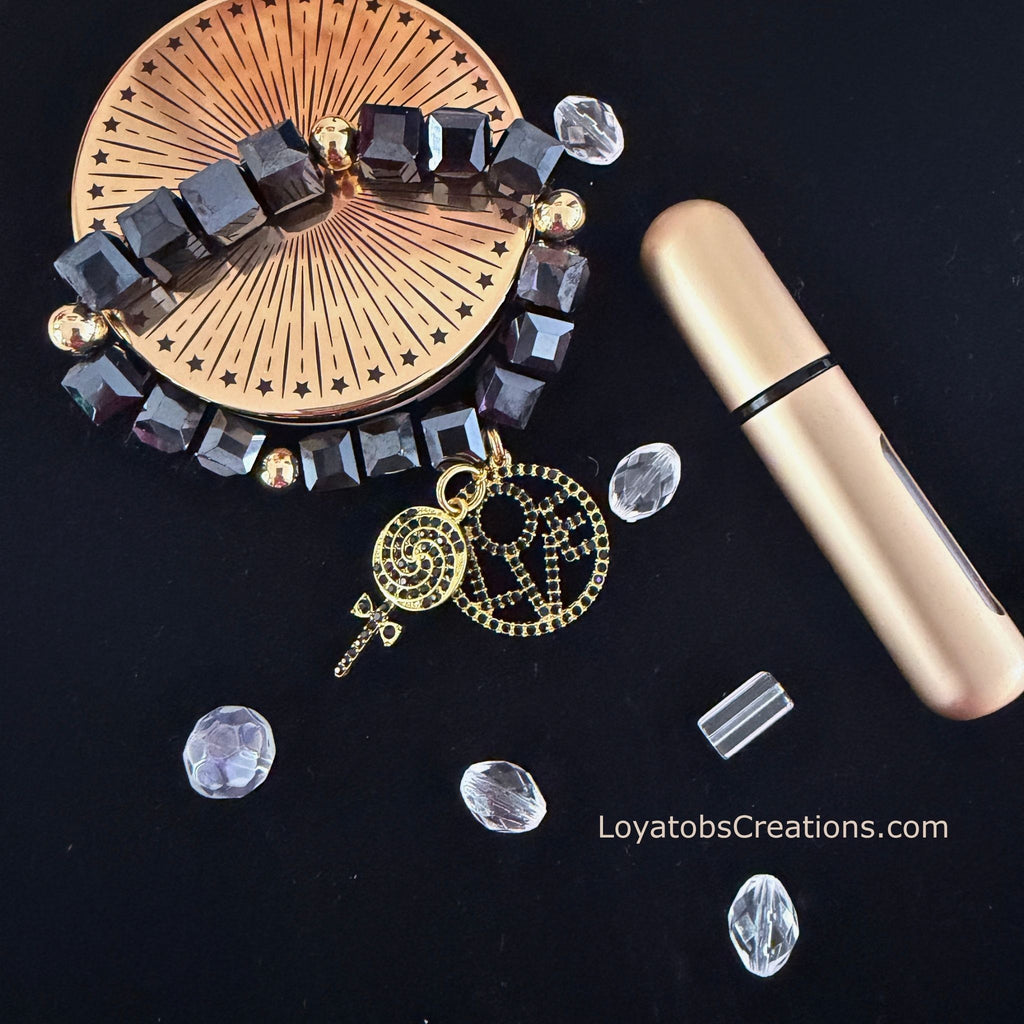 Black cube bead and gold accent bracelet with gold LOVE charm and black crystal lollipop charm flat lay on dark background - LoyatobsCreations.com