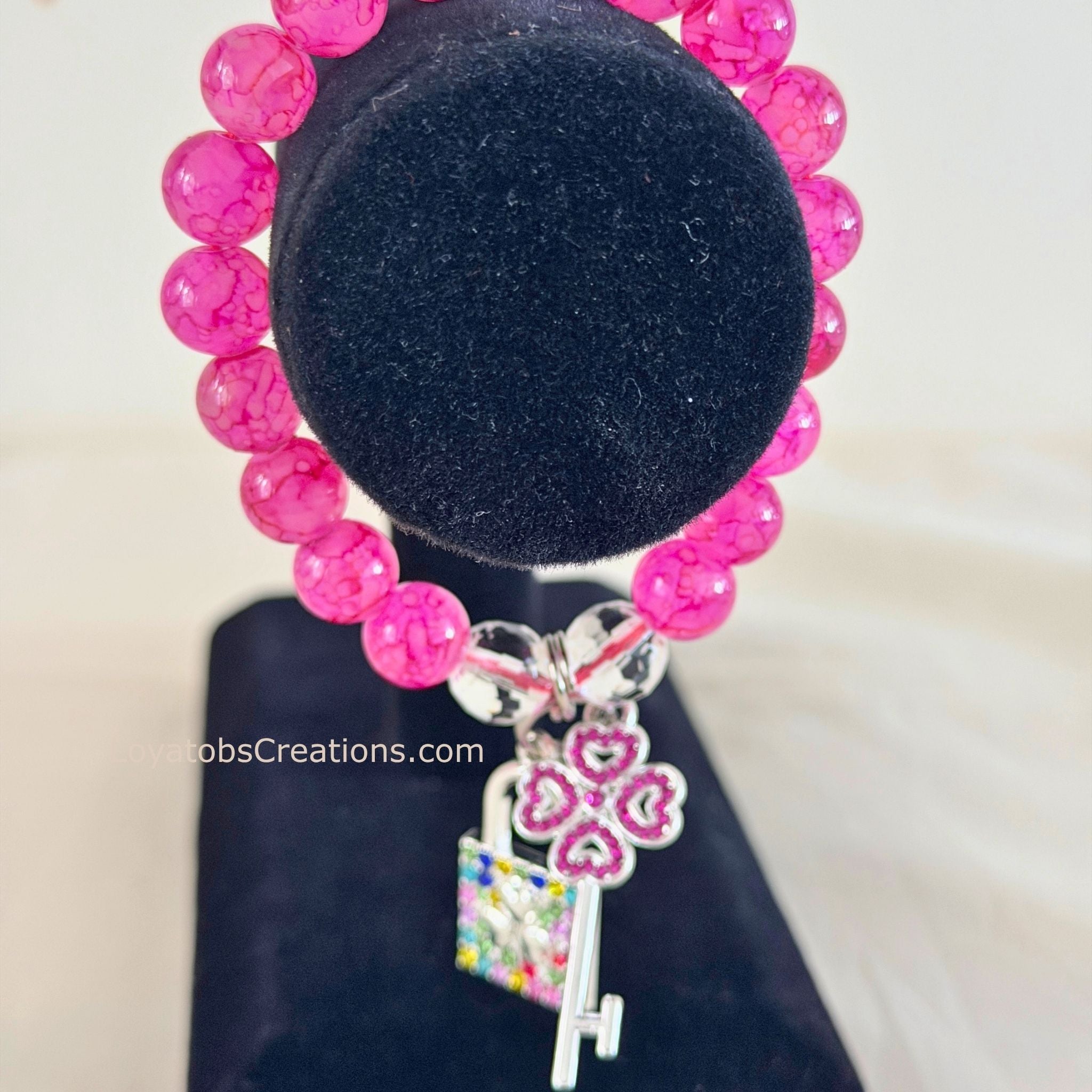 Hot pink crackle bead bracelet with multicolour rhinestone padlock and pink heart key charms on black jewellery stand - LoyatobsCreations.com