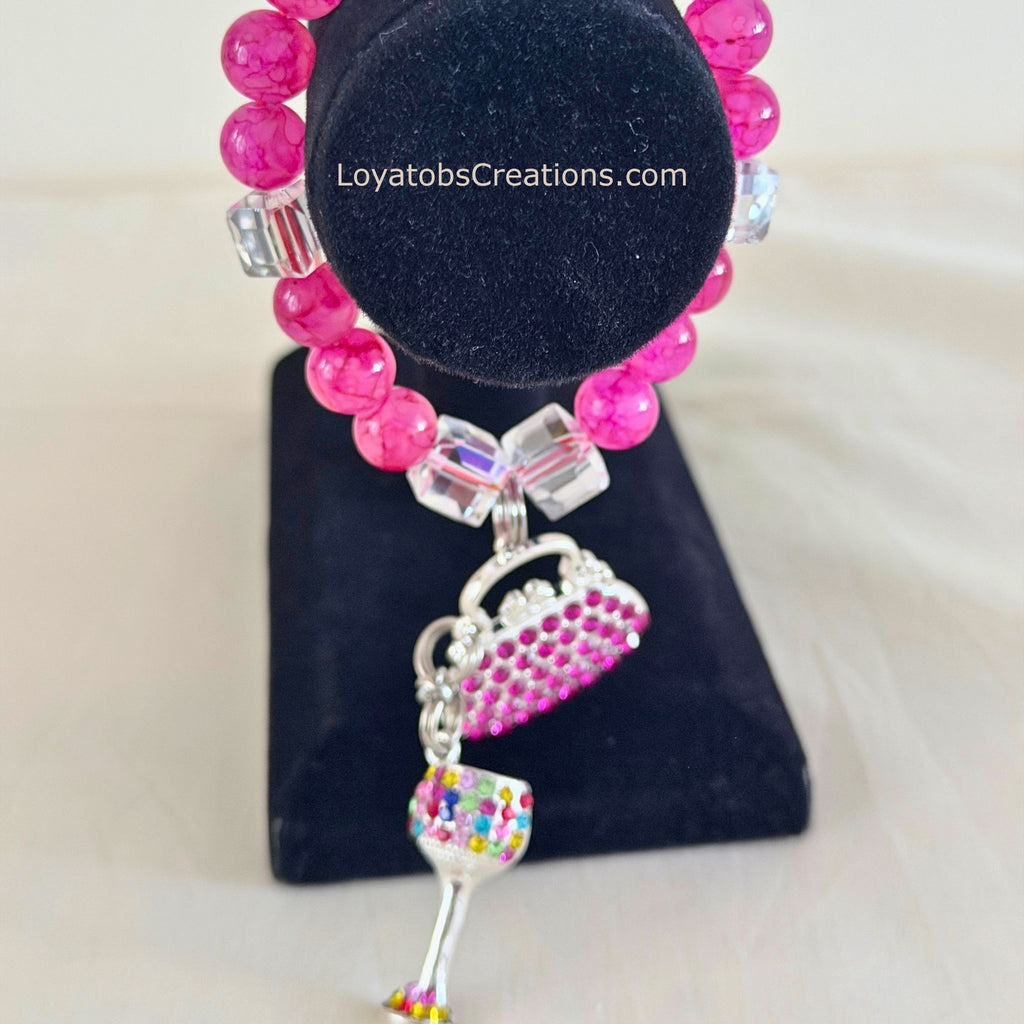 Hot pink crackle bead bracelet with pink rhinestone handbag and multicolour wine glass charms on black jewellery stand - LoyatobsCreations.com