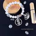 White bead and clear crystal cube bracelet with silver pavé dollar sign and crown charms flat lay on dark background - LoyatobsCreations.com