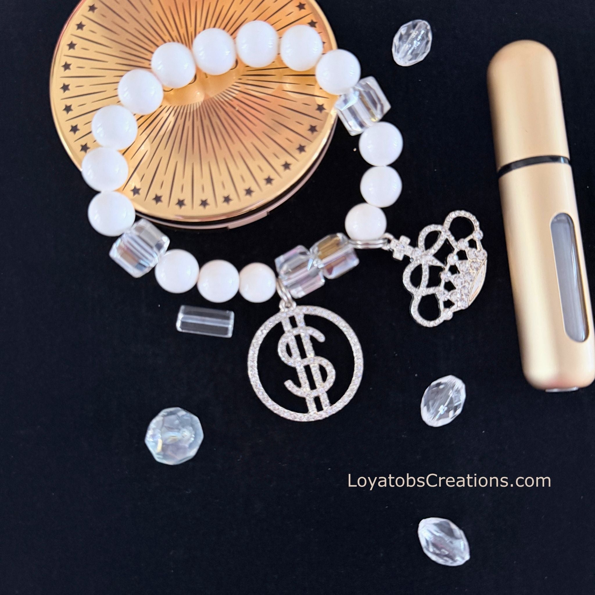 White bead and clear crystal cube bracelet with silver pavé dollar sign and crown charms flat lay on dark background - LoyatobsCreations.com