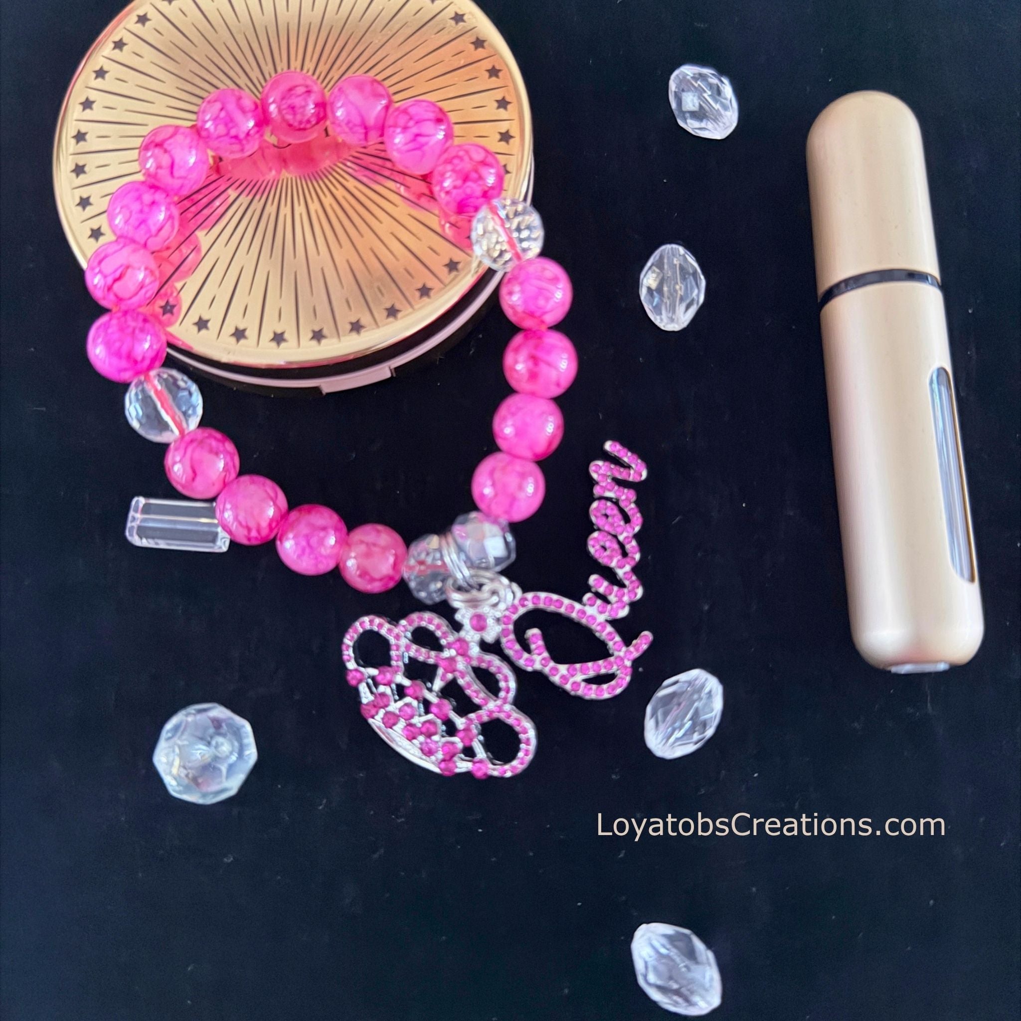 Hot pink crackle bead bracelet with pink rhinestone crown and Queen script charms flat lay on dark background - LoyatobsCreations.com