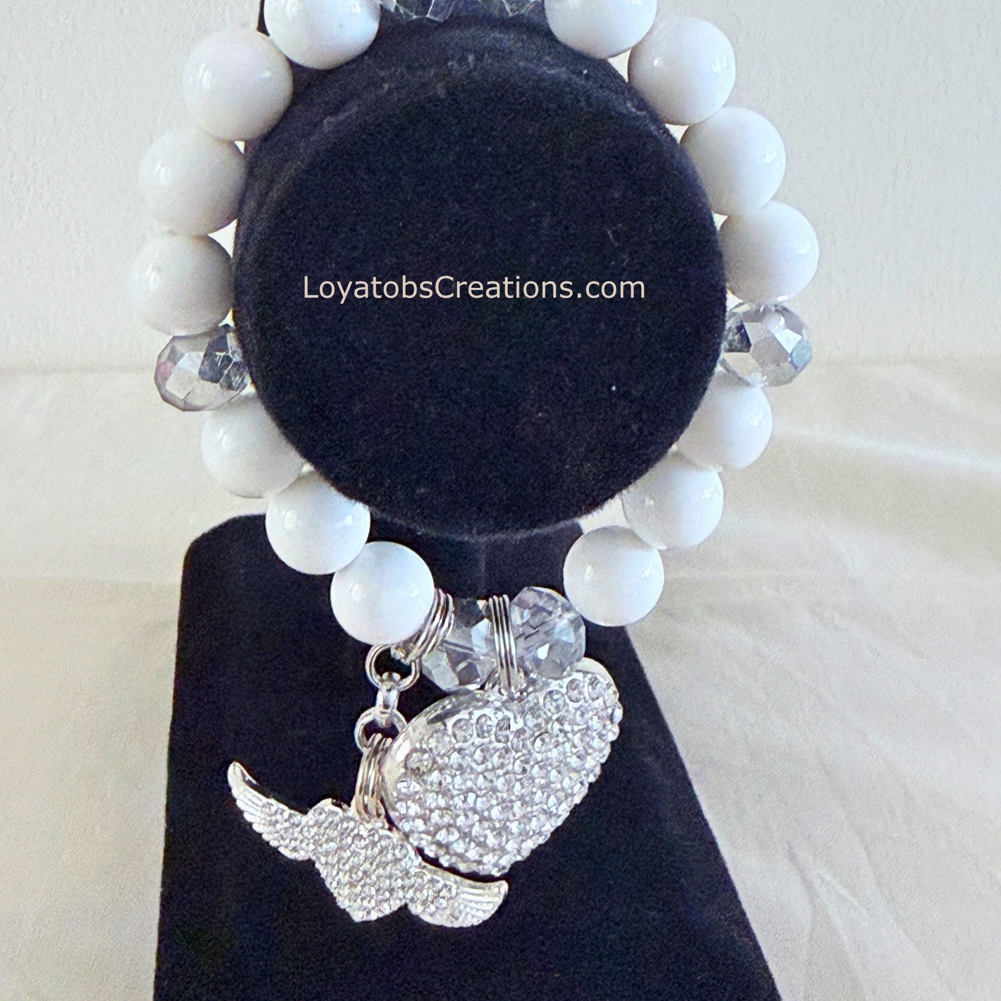 White bead and grey crystal bracelet with silver pavé heart and angel wing charms on black jewellery stand - LoyatobsCreations.com