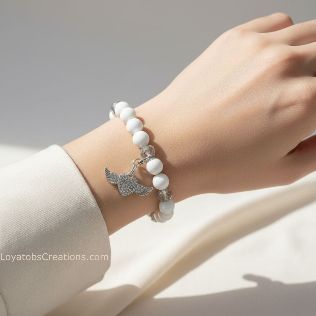 White bead and crystal bracelet with silver pavé heart and angel wing charms worn on wrist - LoyatobsCreations.com
