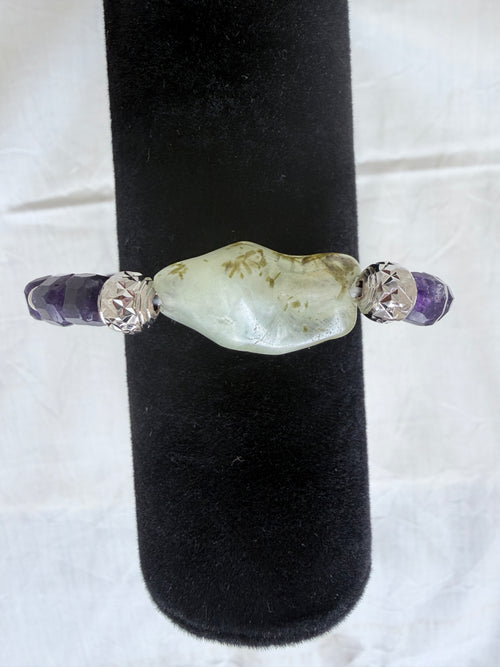 "Close-up of amethyst and green prehnite bracelet on black velvet display stand showing prehnite centrepiece detail"