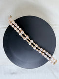 "Freshwater pearl two-row bracelet laid flat on a black circle board showing full bracelet design with gold accessories"