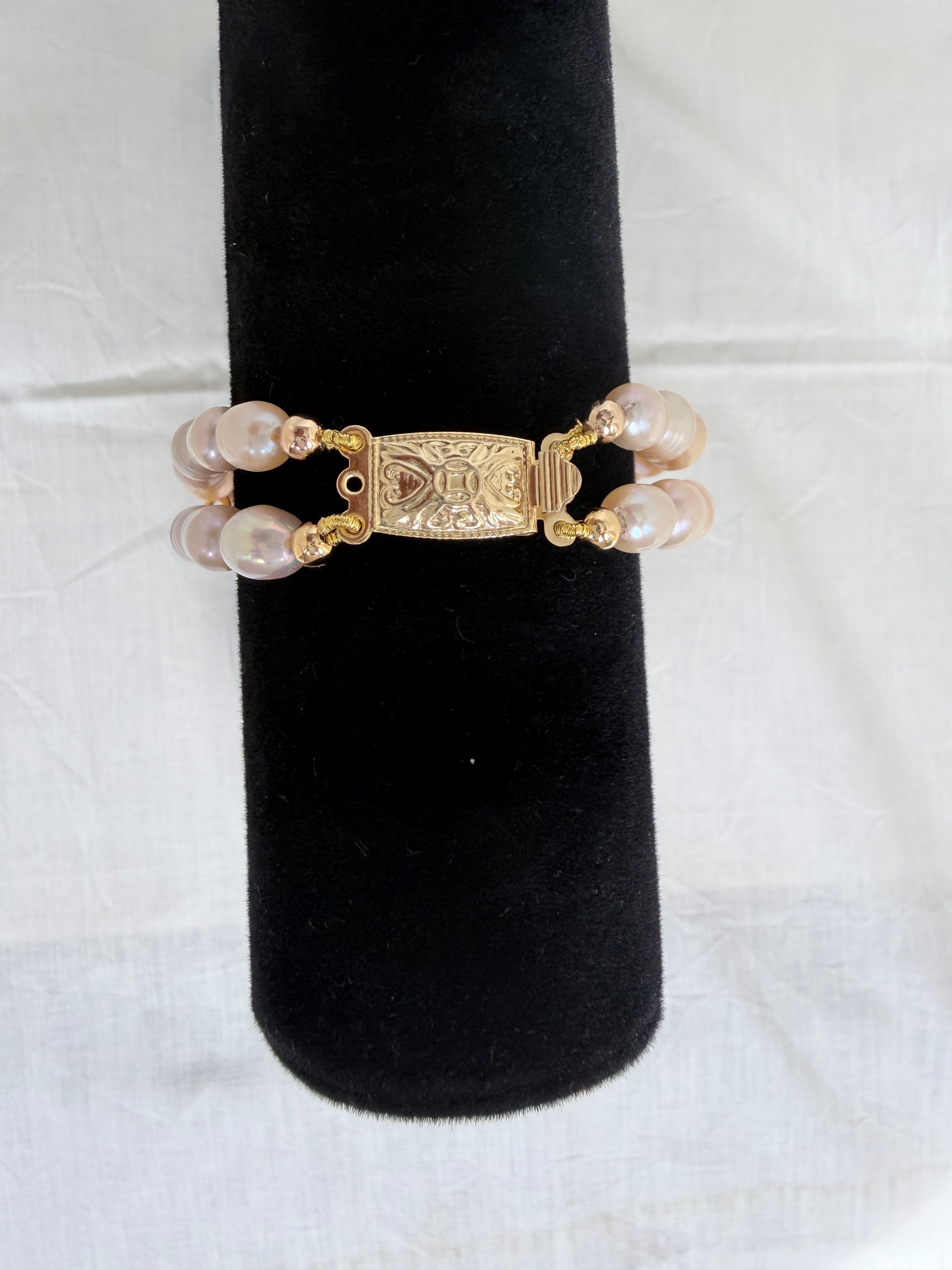 "Close-up of freshwater pearl two-row bracelet on black velvet stand highlighting the decorative gold box clasp"