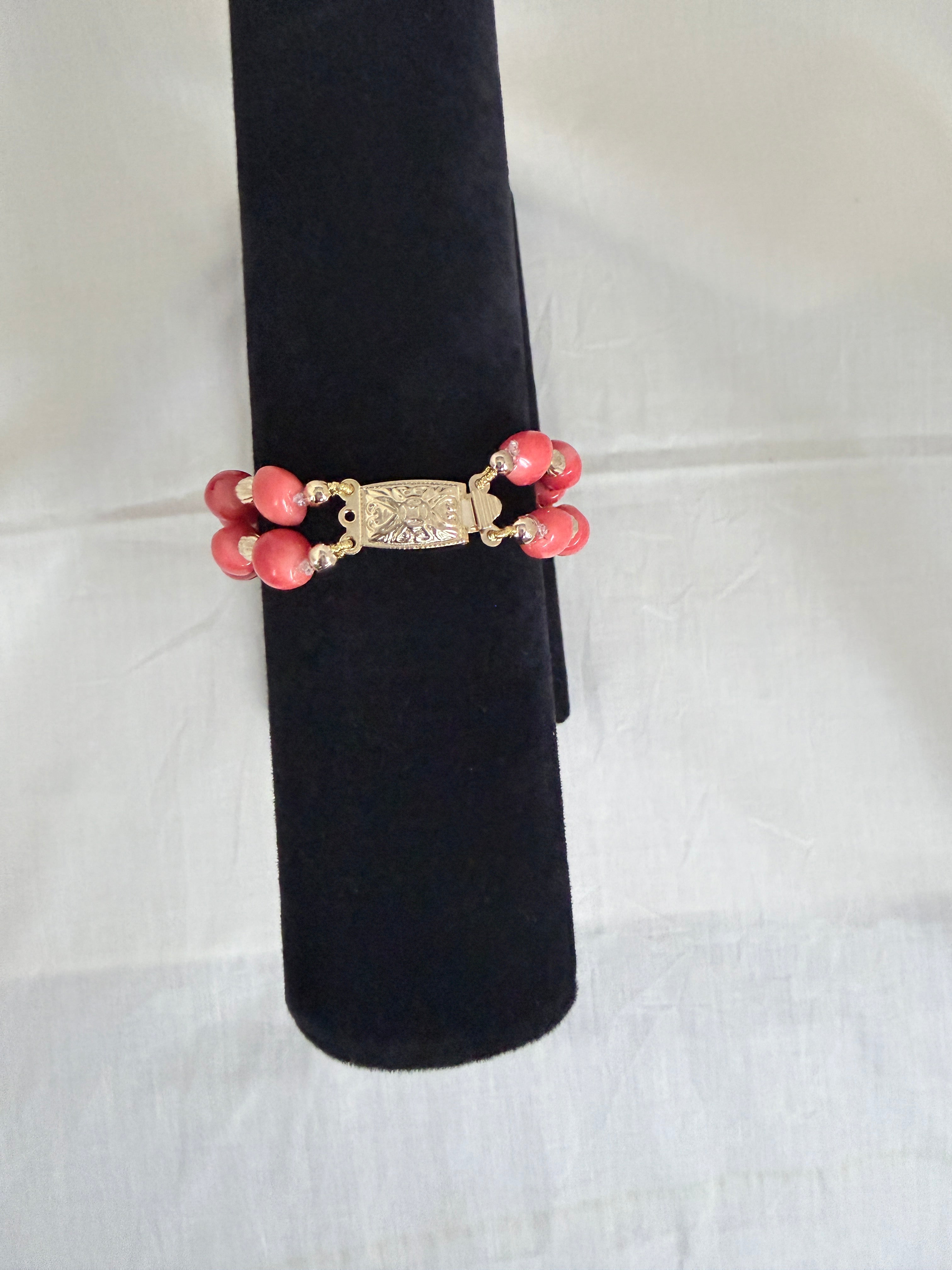 "Close-up of barrel coral two-row bracelet on black velvet stand highlighting the decorative gold box clasp"