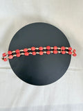 "Barrel coral two-row bracelet laid flat on a dark circle board showing full bracelet design with gold accessories"