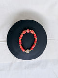 "Mixed coral barrel bracelet with CZ fish hook clasp laid flat on a black circle board showing full bracelet and round CZ clasp"