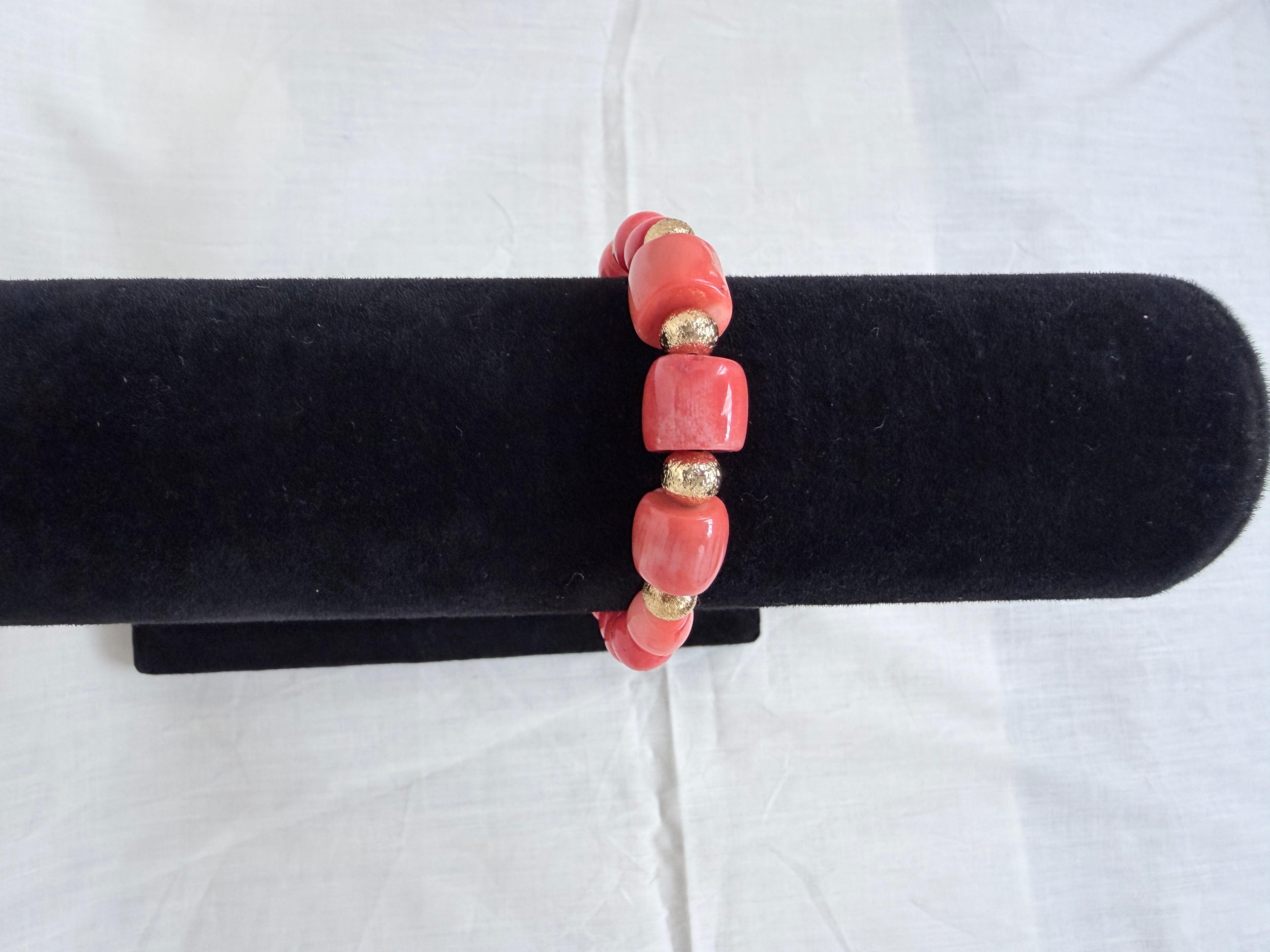 "Mixed coral barrel bracelet with CZ fish hook clasp on black velvet stand showing side view of chunky coral barrel beads and textured gold rondelles"