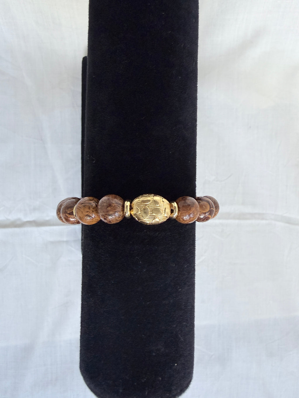 "Elephant skin jasper bracelet on black velvet stand showing close-up of ornate gold oval centrepiece bead with marbled brown jasper beads"