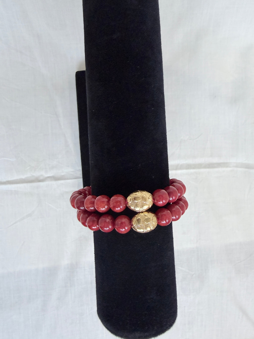 "Two coral jade bracelets stacked on black velvet stand showing how they look layered together"