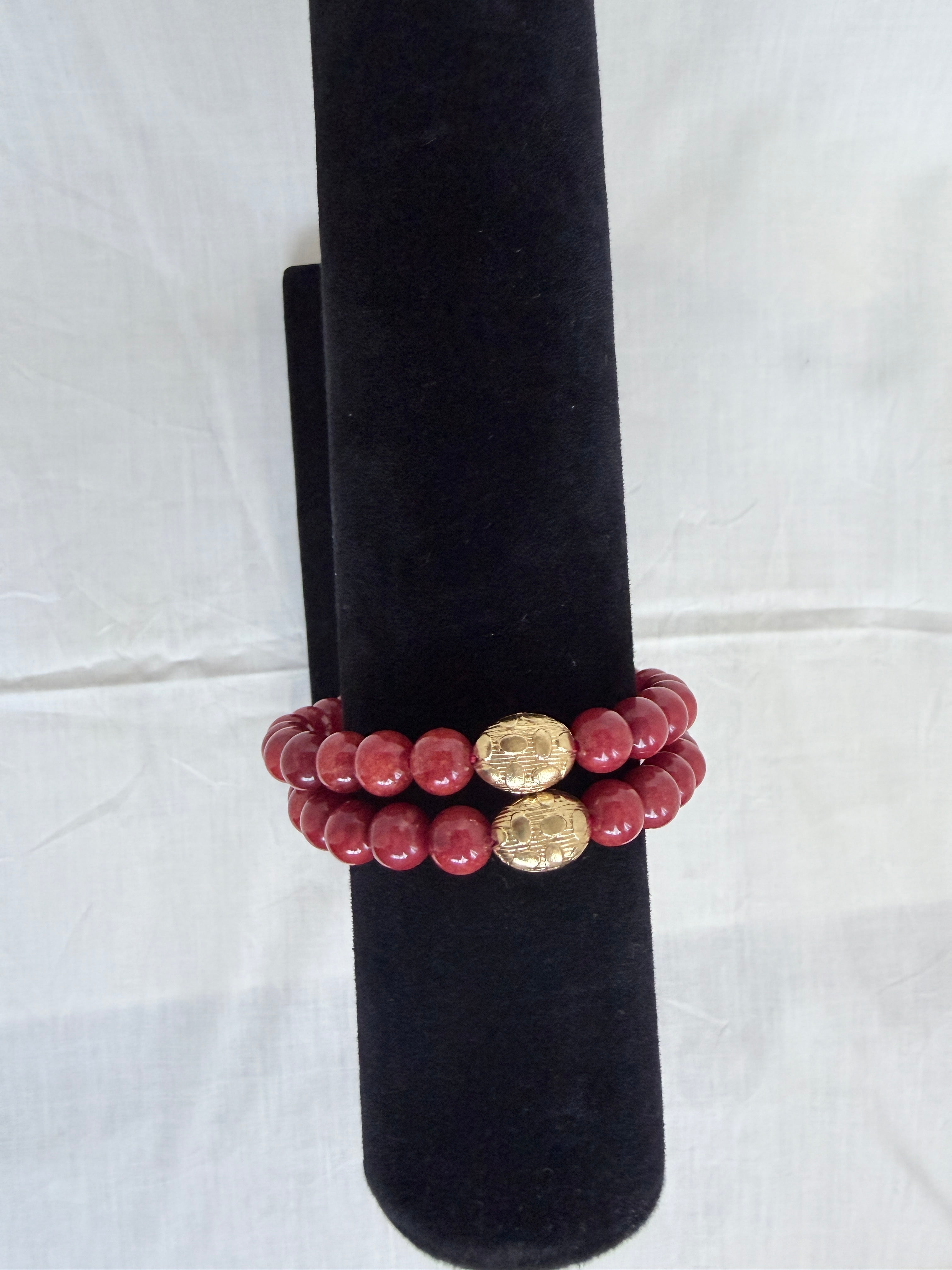 "Two coral jade bracelets stacked on black velvet stand showing how they look layered together"