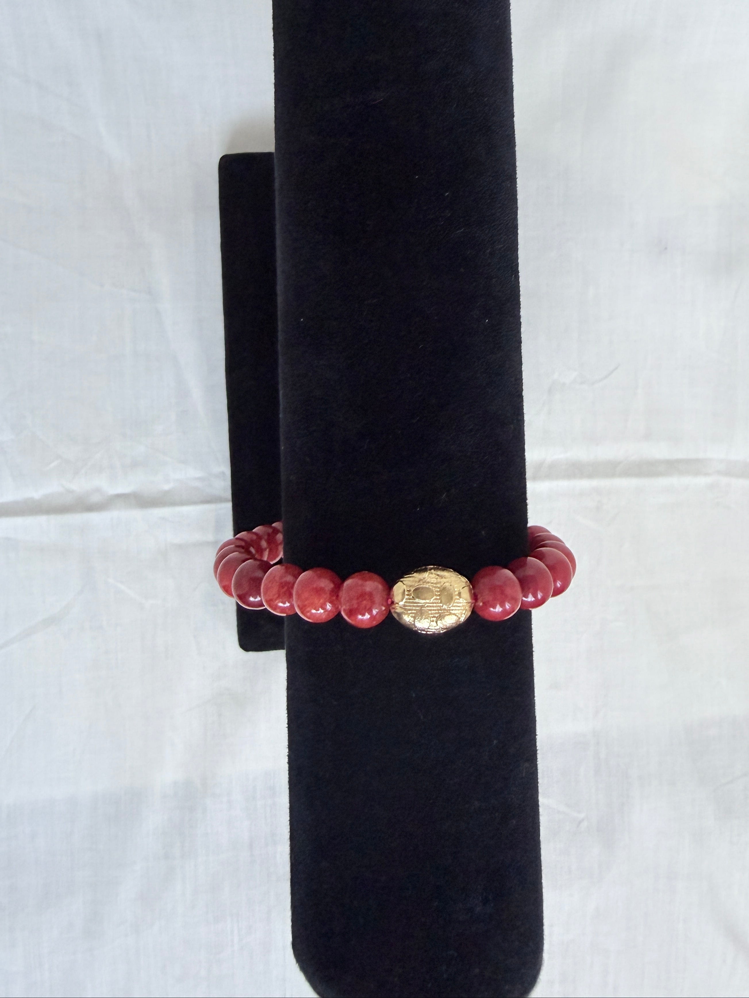 "Coral jade bracelet on black velvet stand showing close-up of ornate gold oval centrepiece bead with round coral jade beads"