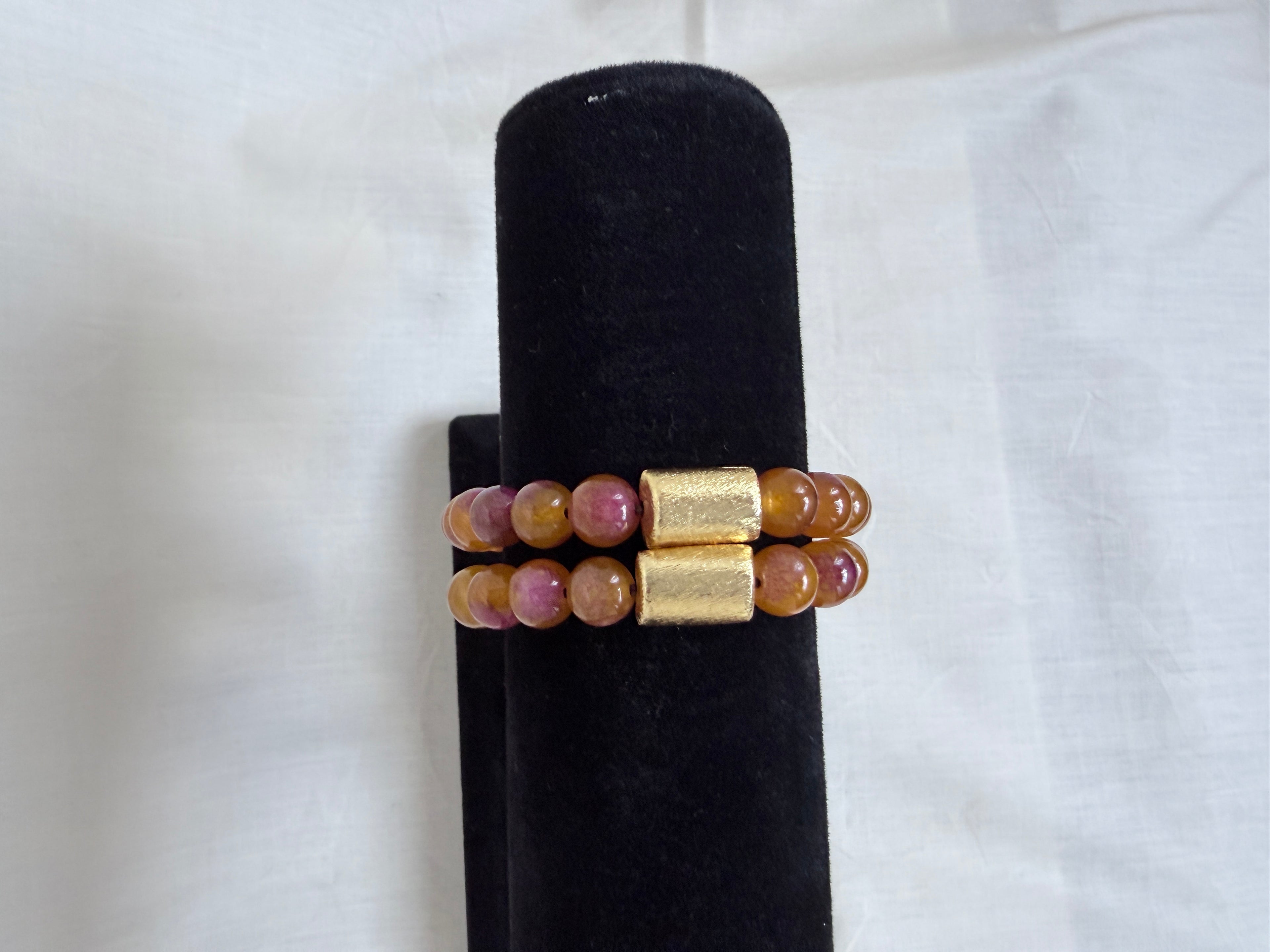 "Two multi bronze jade bracelets stacked on black velvet stand showing how they look layered together with gold barrel beads"