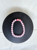 "Pink jade and candy bracelet laid flat on a black circle board showing full bracelet shape and gold rondelle centrepiece"