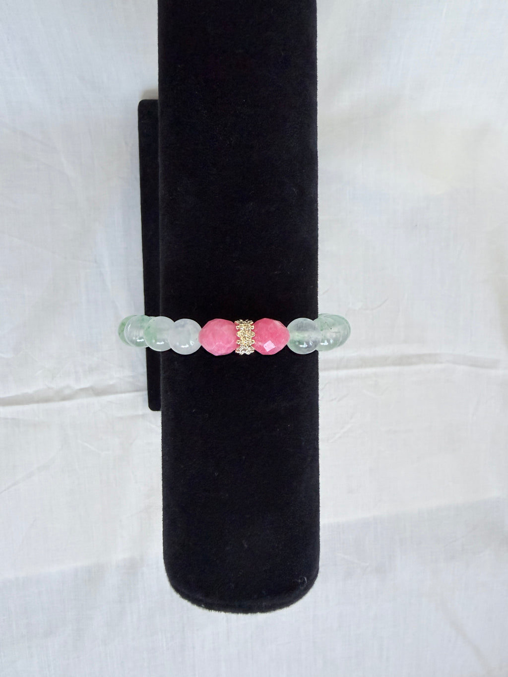 "Mint green jade and candy bracelet on black velvet stand showing close-up of pink candy bead and gold CZ rondelle with translucent mint green jade beads"
