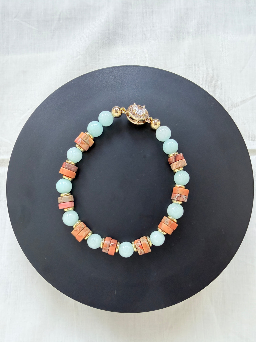 "Jasper and aqua agate bracelet laid flat on a black circle board showing full bracelet with earthy jasper wheel beads, aqua agate beads and CZ fish hook clasp"