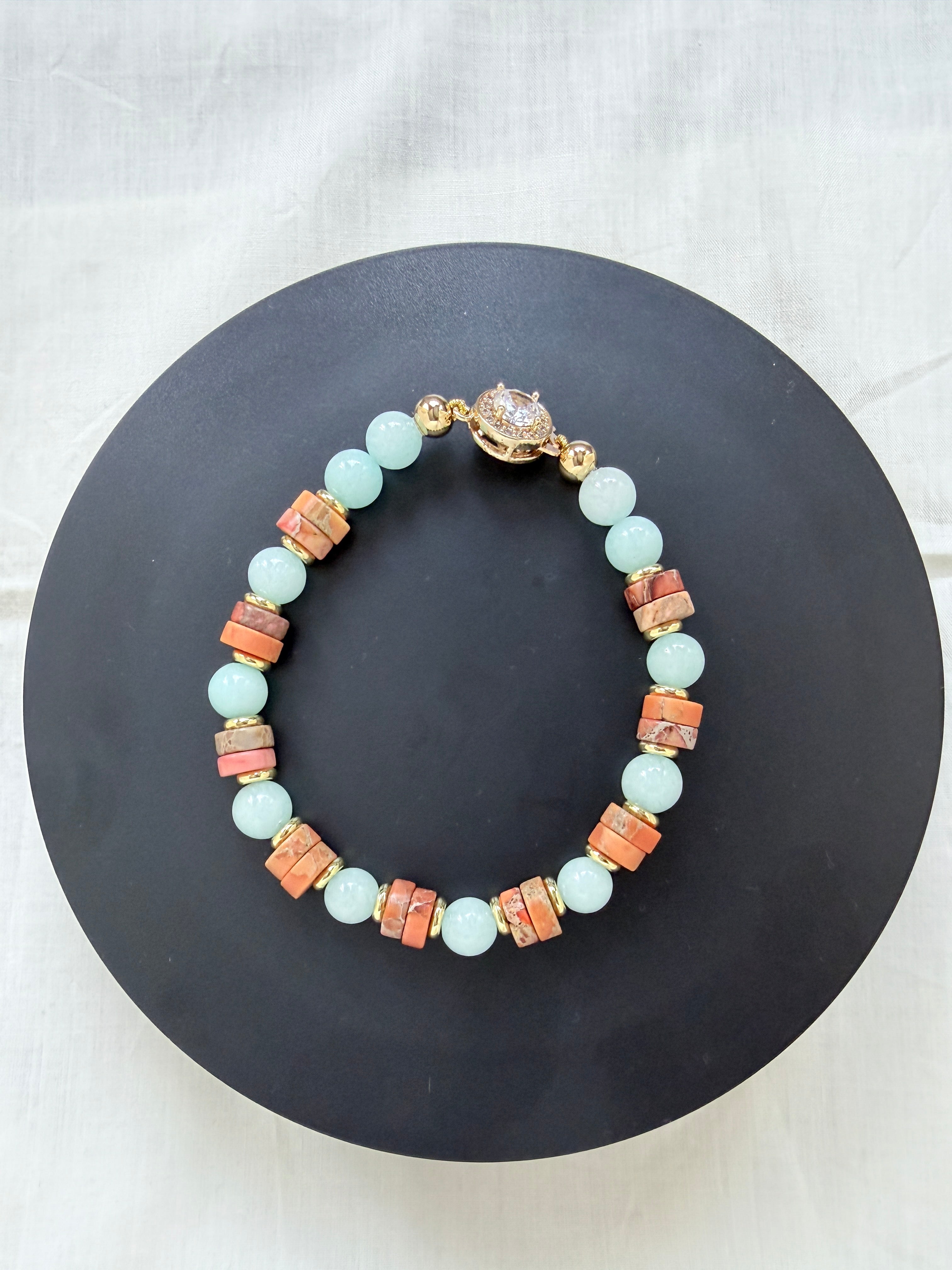 "Jasper and aqua agate bracelet laid flat on a black circle board showing full bracelet with earthy jasper wheel beads, aqua agate beads and CZ fish hook clasp"