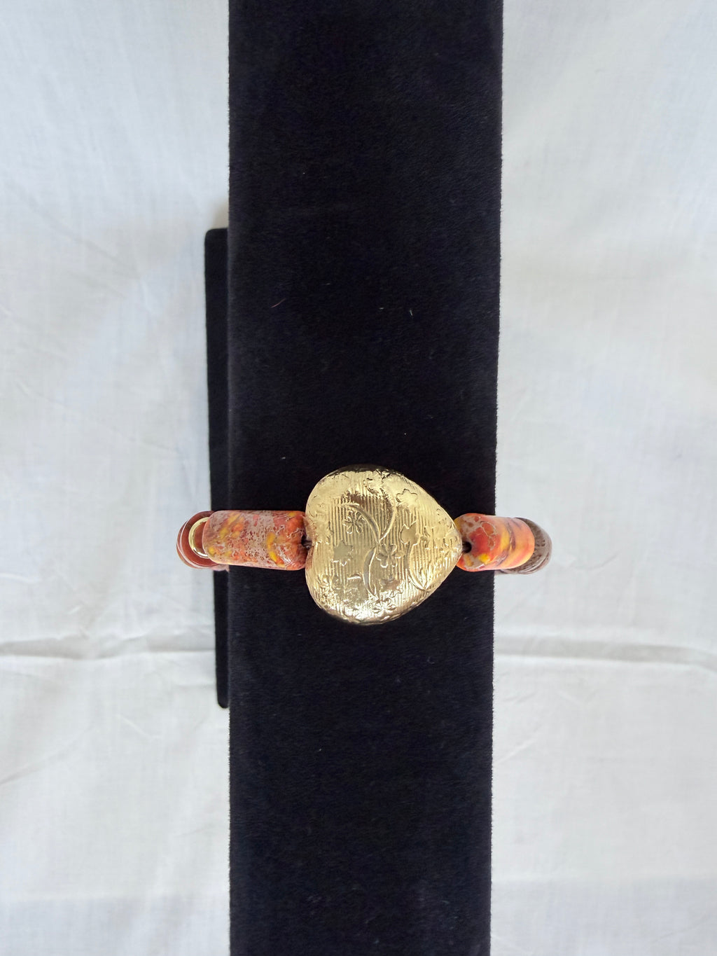 "Jasper heart bracelet on black velvet stand showing close-up of large engraved brass heart focal bead with imperial jasper tube beads"