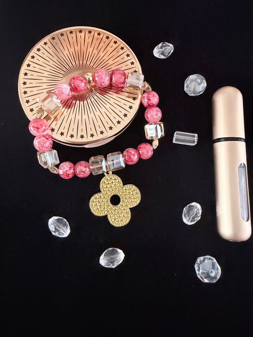 Flower Power Charm Bracelet flat lay on black velvet with scattered clear rhinestones and perfume bottle showing gold flower charm