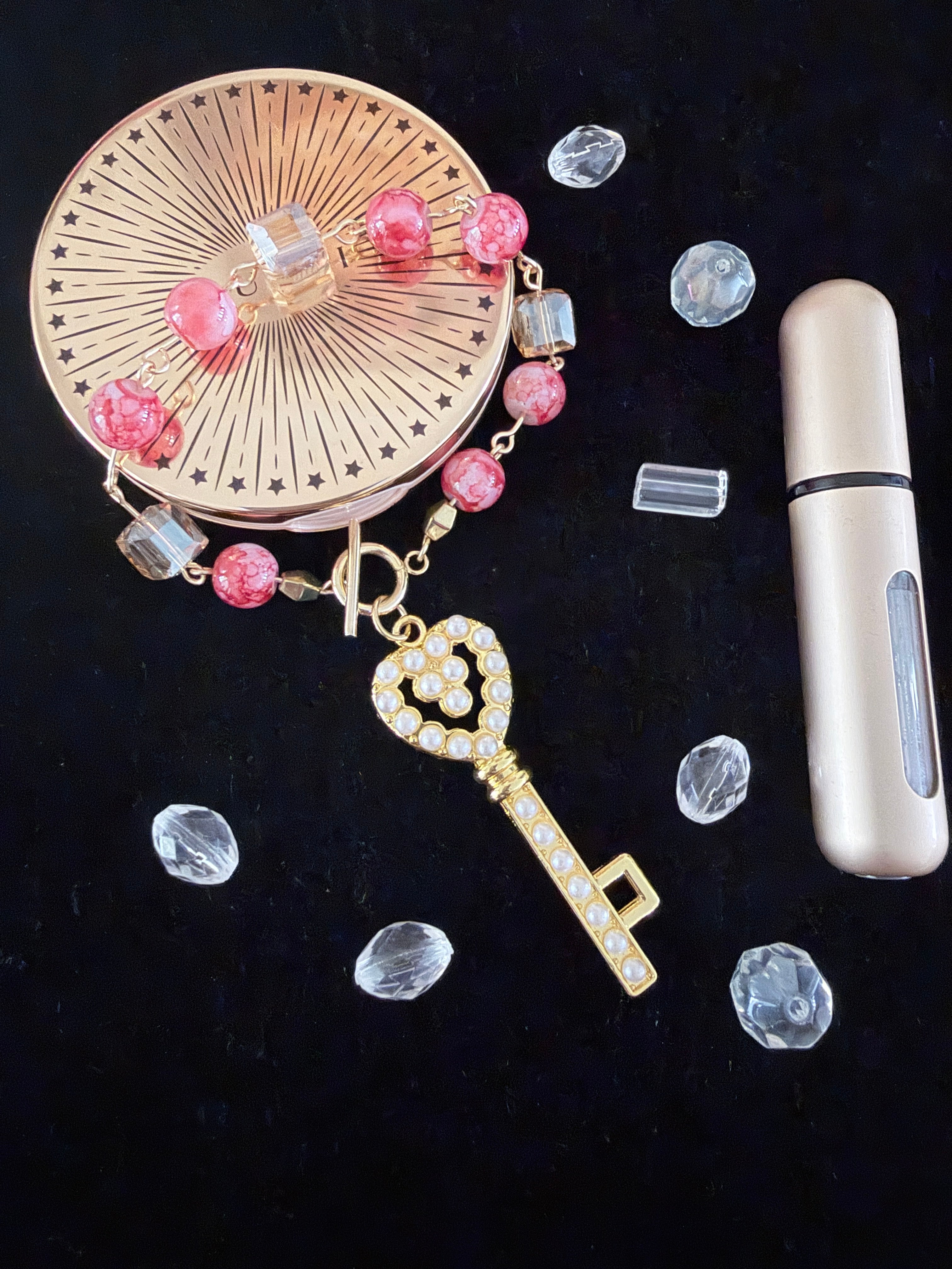 Key to My Heart Charm Bracelet flat lay on black velvet with scattered clear rhinestones and perfume bottle showing pearlised gold key charm