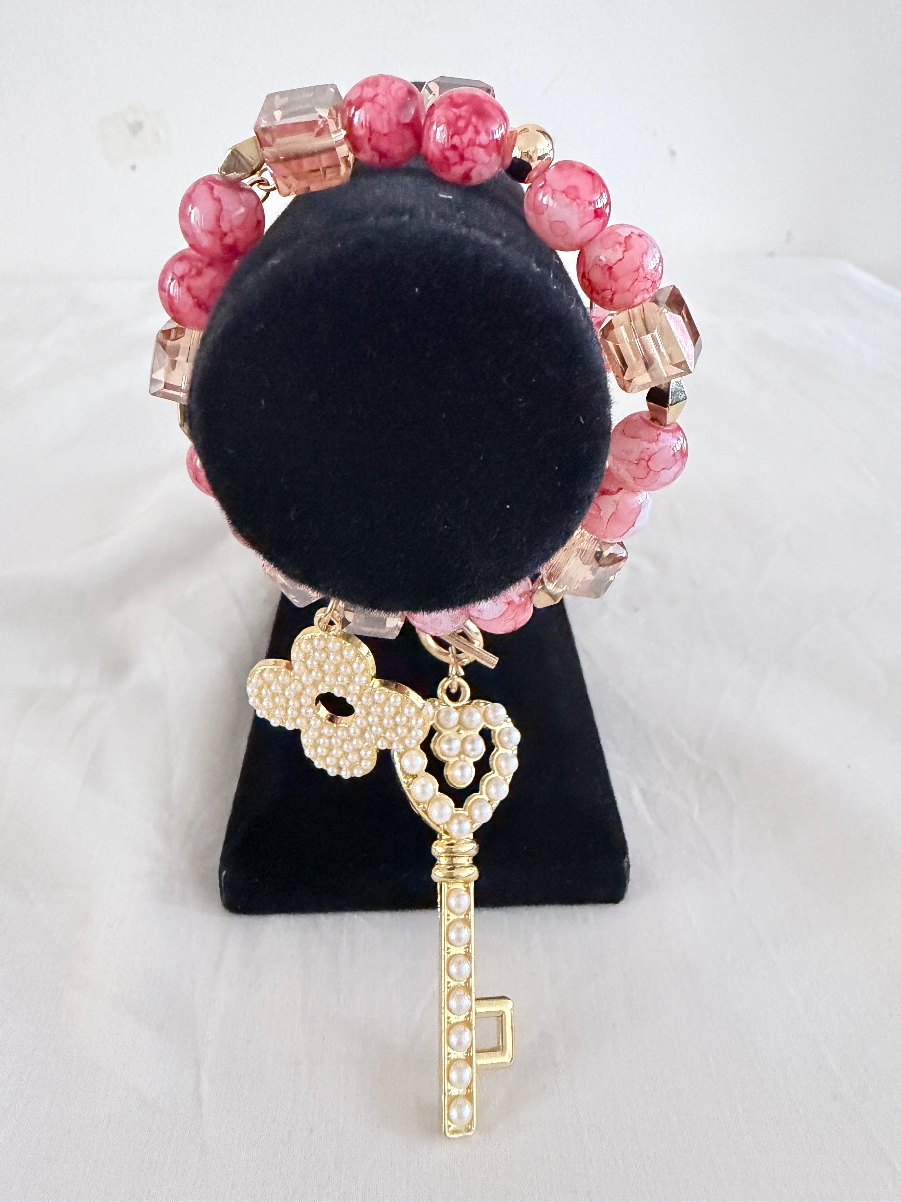 Key to My Heart Charm Bracelet on black velvet stand close up showing pearlised gold key charm detail with pink orange and champagne cube beads