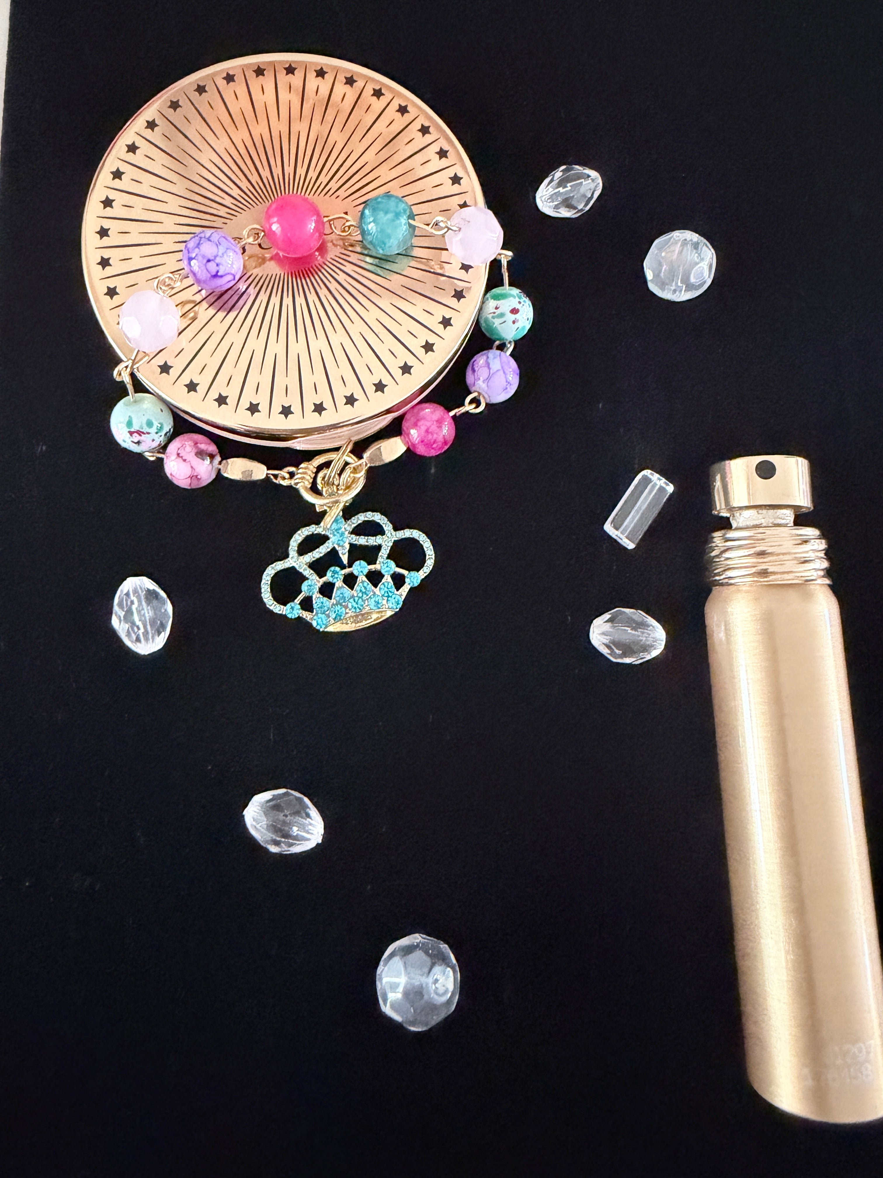 Queen of Everything Charm Bracelet flat lay on black velvet with scattered clear rhinestones and gold perfume bottle showing teal rhinestone gold crown charm
