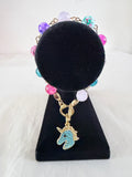 Wild and Free Charm Bracelet on black velvet stand showing teal rhinestone gold unicorn head charm with multicolour pink purple lavender and teal beads on gold link chain