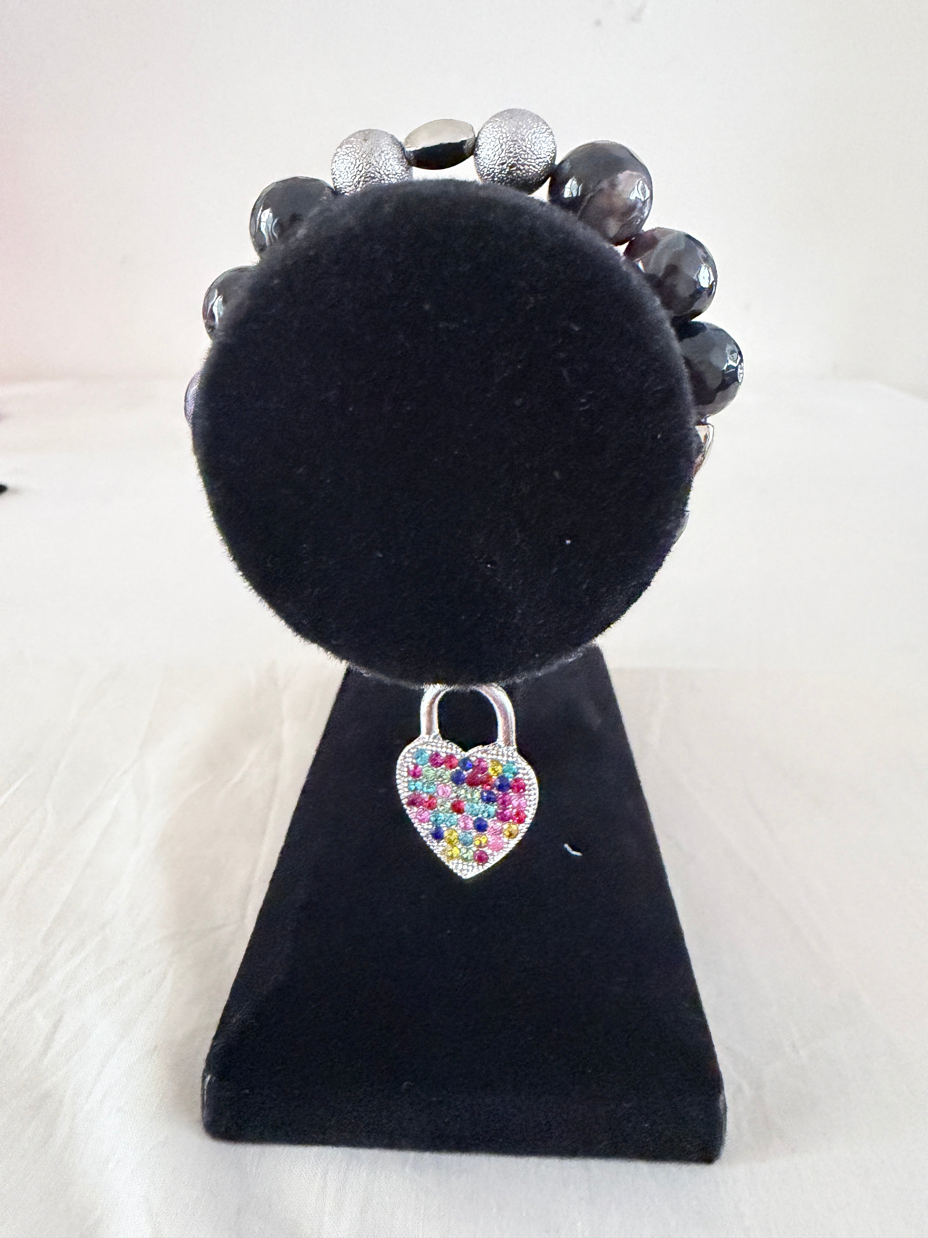 Locked in Love Charm Bracelet on black velvet stand showing multicolour rhinestone silver heart padlock charm with purple banded agate and silver stardust beads