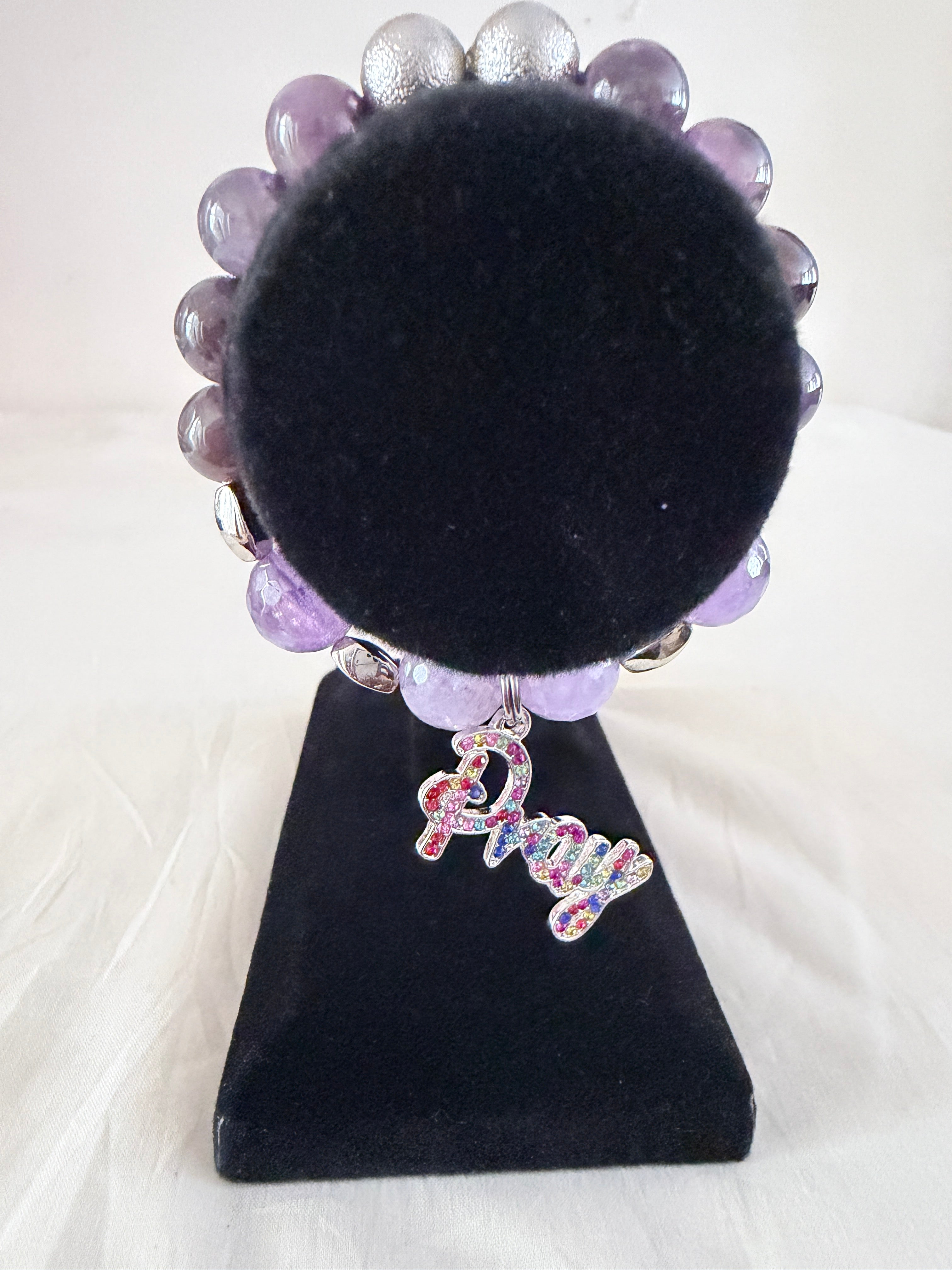 Faith and Grace Charm Bracelet on black velvet stand showing multicolour rhinestone silver Pray script charm with natural amethyst and silver stardust beads
