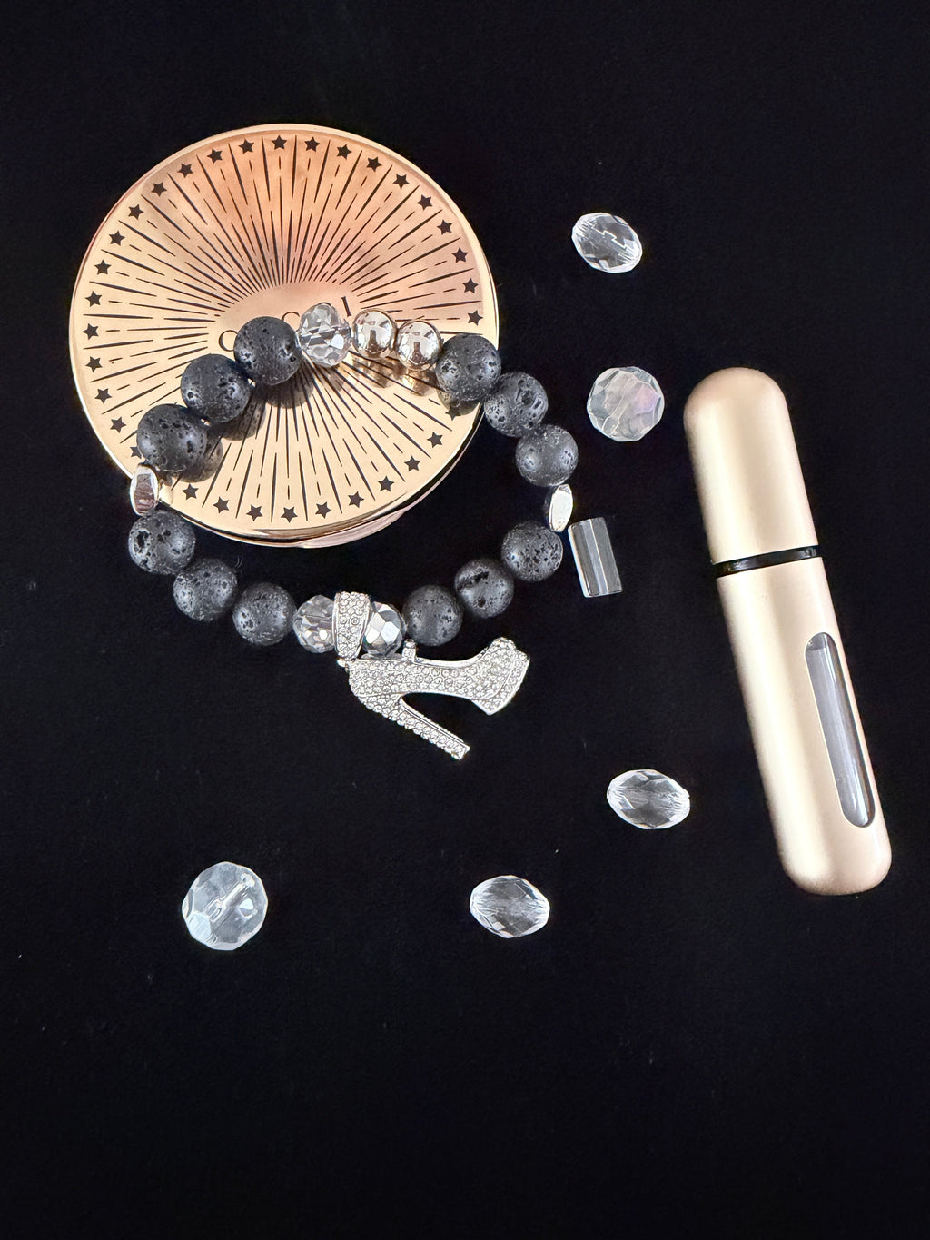 She Walks in Beauty Charm Bracelet flat lay on black velvet with scattered clear rhinestones and gold perfume bottle showing silver rhinestone stiletto heel charm