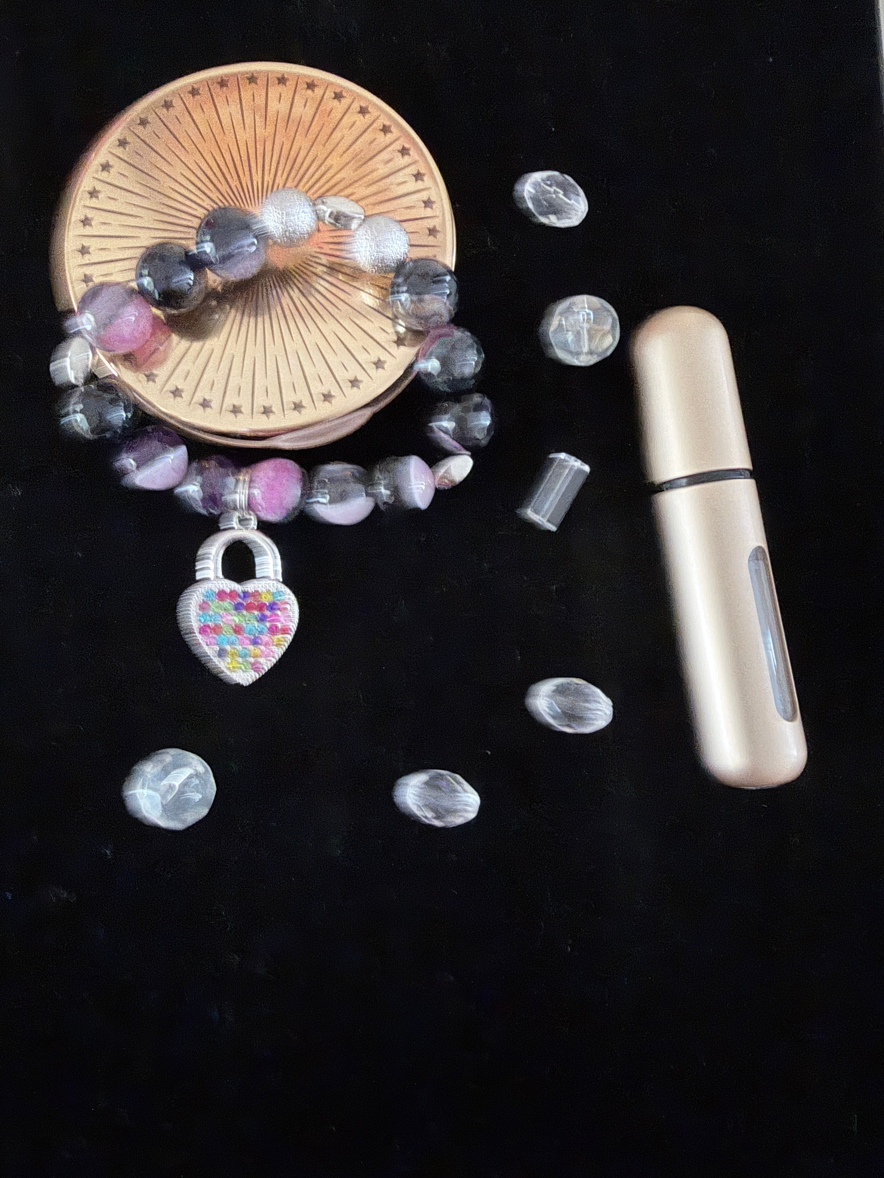Locked in Love Charm Bracelet flat lay on black velvet with scattered clear rhinestones and perfume bottle showing multicolour heart padlock charm