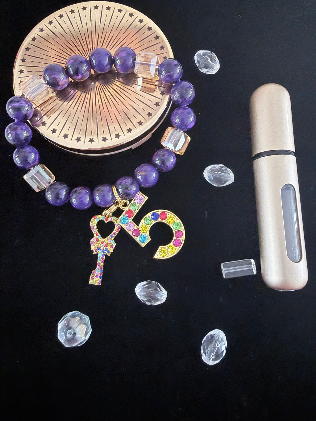 Purple bead and champagne cube crystal charm bracelet with multicolour rhinestone charms on dark background
