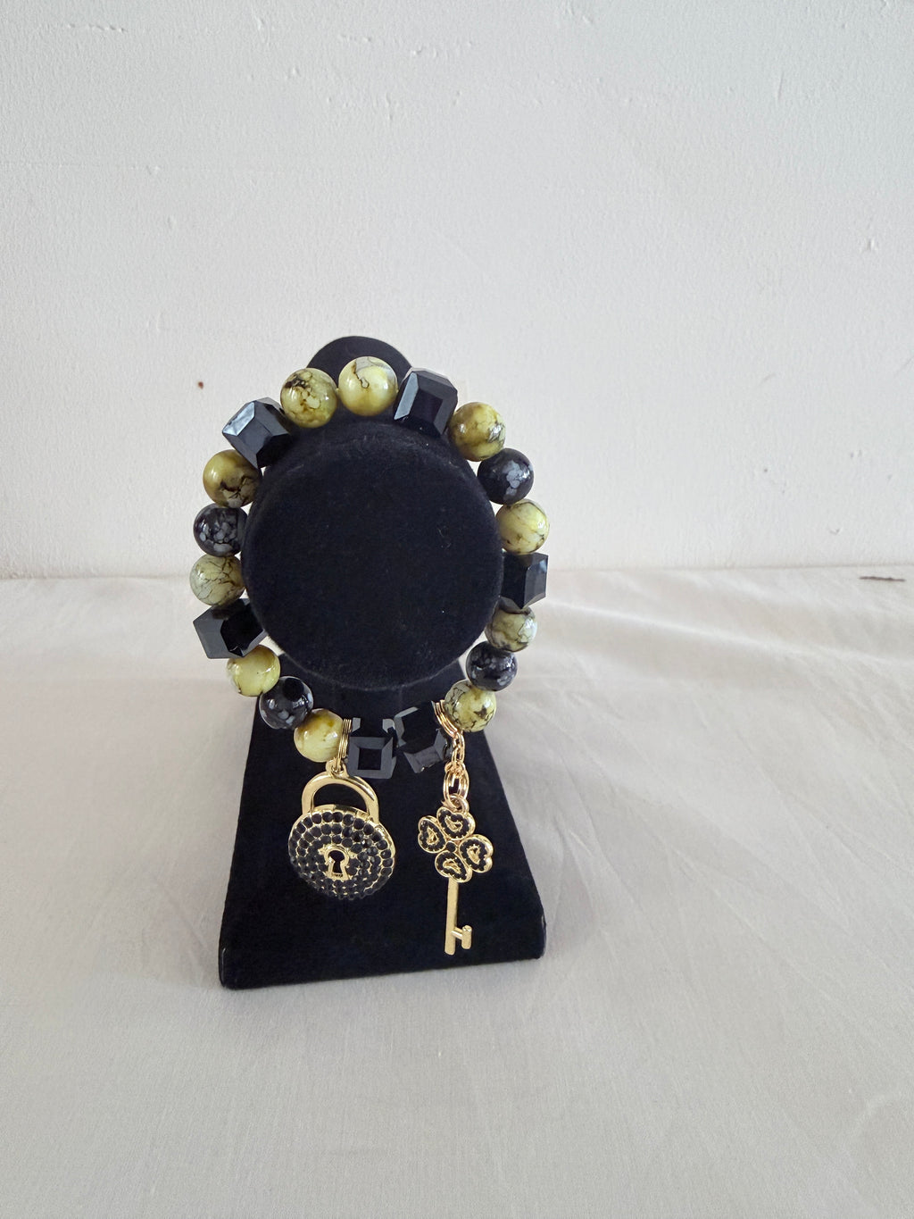 Lime and black cube bead bracelet with gold lock and key charms on black jewellery stand