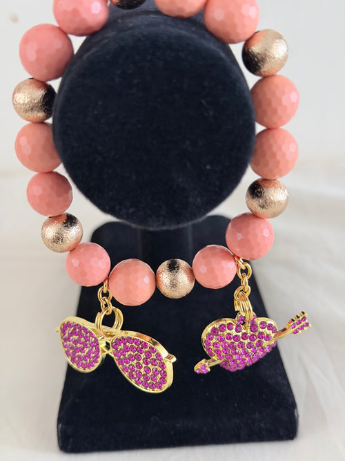 Blush pink and gold bead bracelet with purple rhinestone sunglasses and heart arrow charms on black jewellery stand - LoyatobsCreations.com