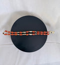 "Coral tube two-row bracelet laid flat on a black circle board showing full length and double row design with gold accessories"