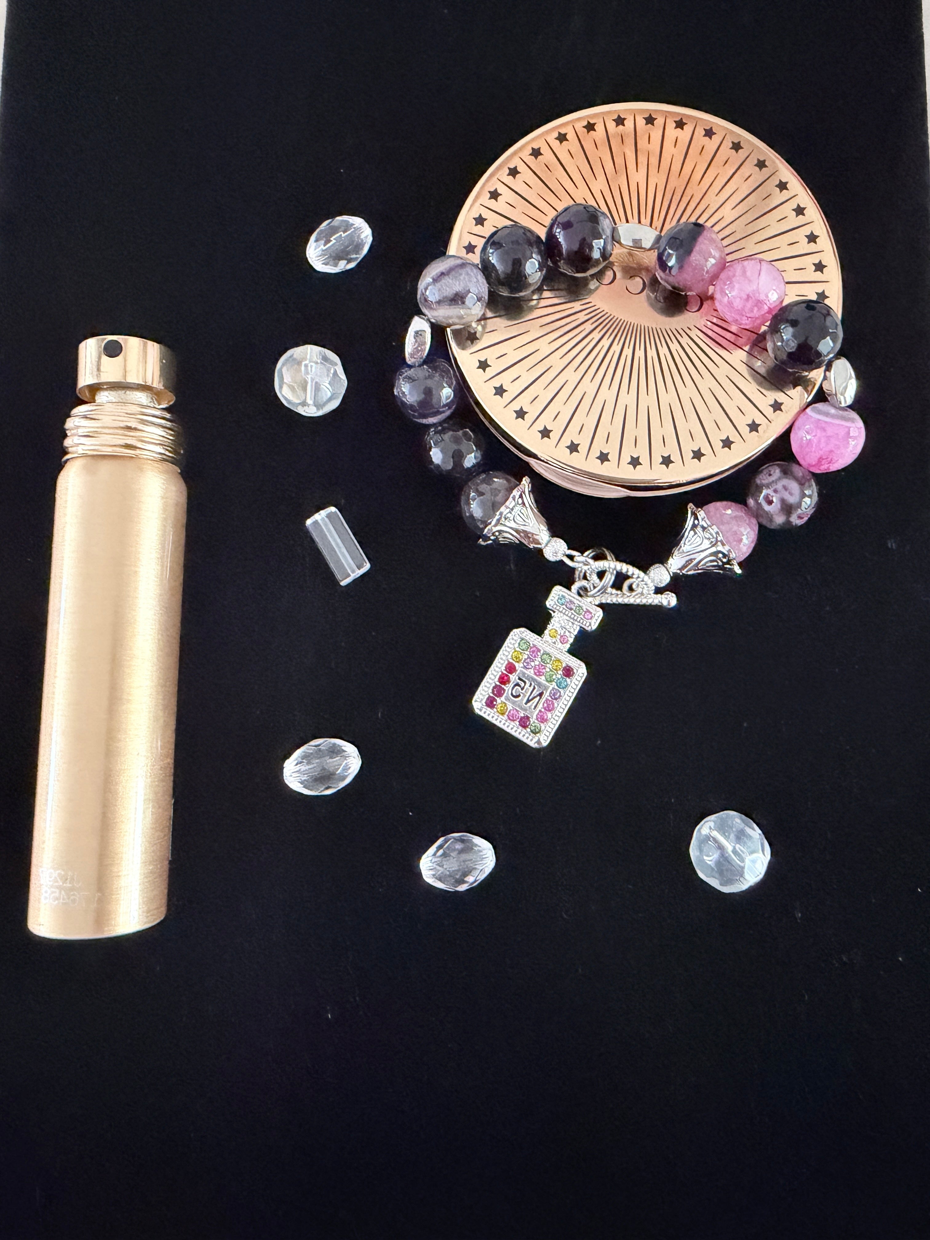 Scent of Luxury Charm Bracelet flat lay on black velvet with scattered clear rhinestones and gold perfume bottle showing multicolour rhinestone perfume bottle charm