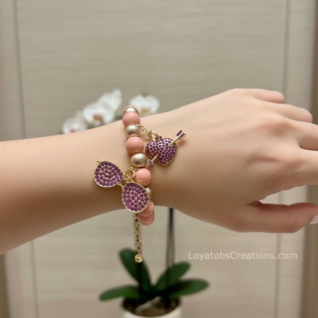 Blush pink and gold bead bracelet with purple rhinestone sunglasses and heart arrow charms worn on wrist - LoyatobsCreations.com