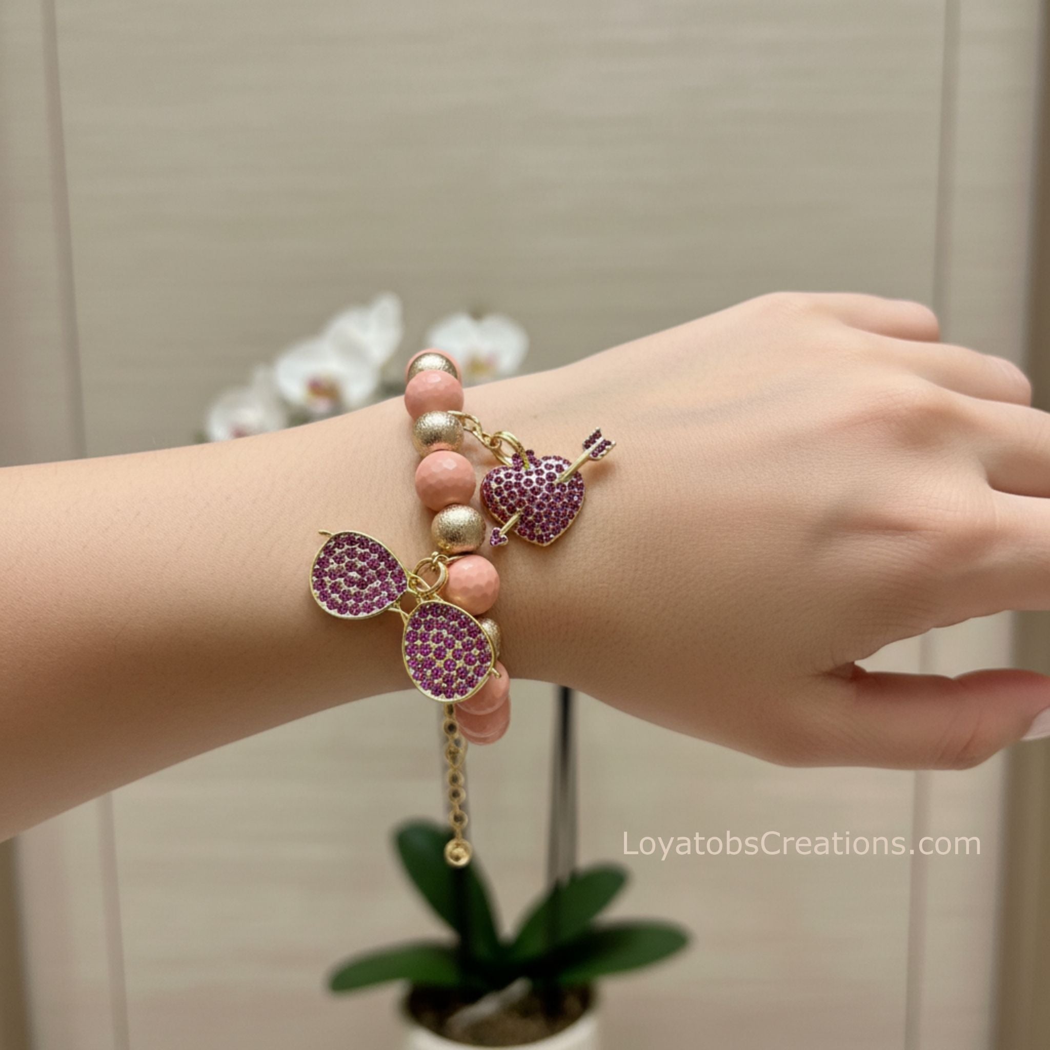 Blush pink and gold bead bracelet with purple rhinestone sunglasses and heart arrow charms worn on wrist - LoyatobsCreations.com