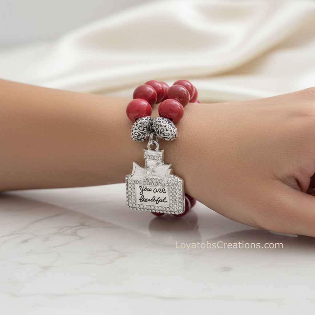 Coral ceramic bead bracelet with silver rhinestone You Are Beautiful perfume bottle charm worn on wrist on marble background - LoyatobsCreations.com