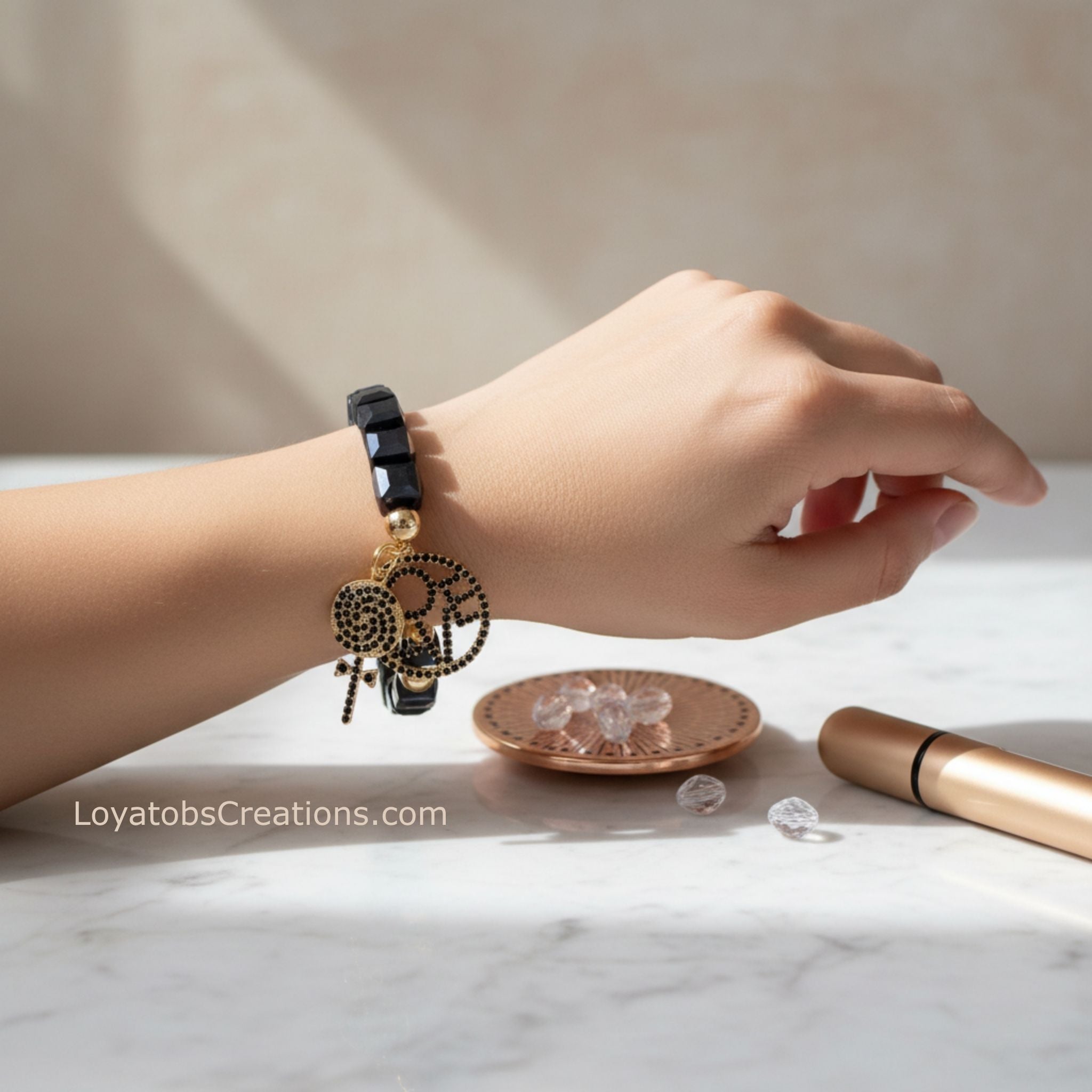 Black cube bead bracelet with gold LOVE charm and black crystal lollipop charm worn on wrist - LoyatobsCreations.com